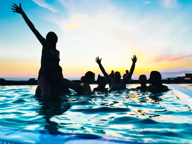 People in a pool at sunset.